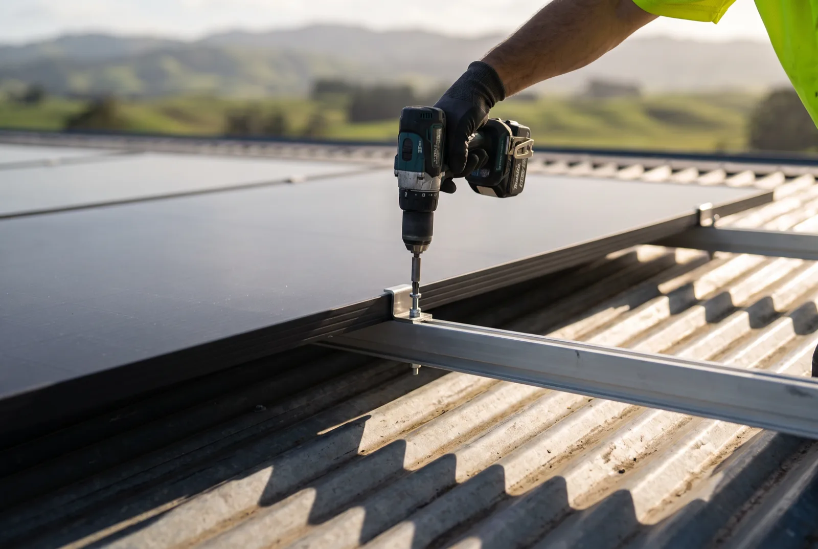 An installer fixing a mounting clamp to a rail on a New Zealand rooftop.